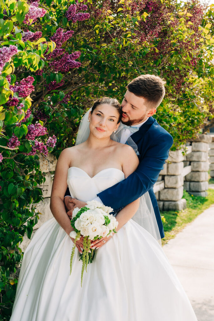 Newlywed couple embracing in front of floral bush