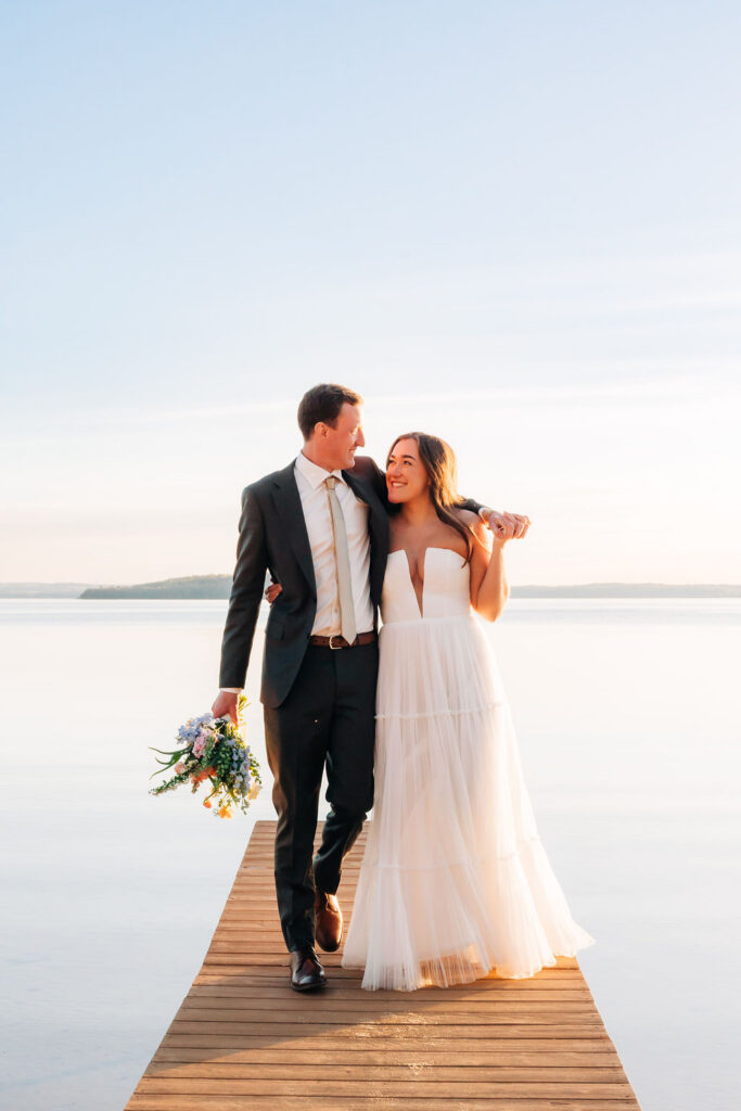 Bride and groom standing on dock over west bay in Traverse City