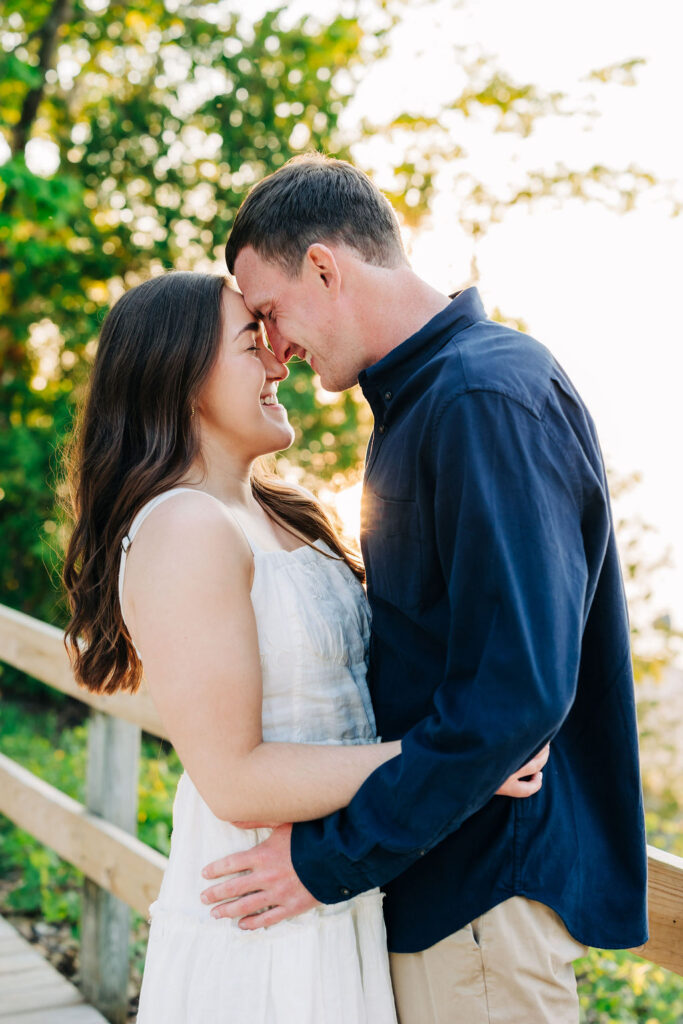 Man and woman embracing in front of fence, trees and beach